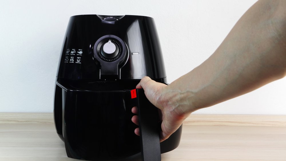 hand grasping handle of black air fryer