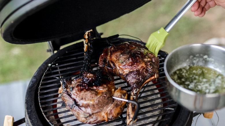 Person glazing meat on grill