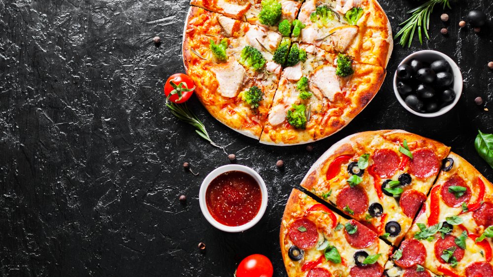 Pizza topped with tomatoes, broccoli, and pepperoni and olives