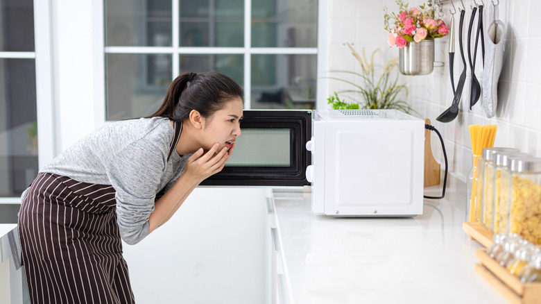 Woman looking into microwave 
