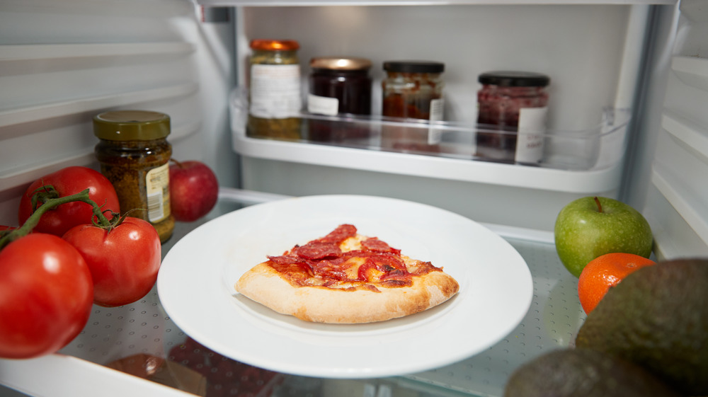 Slice of pizza on a plate in the refrigerator