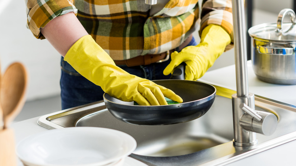Person cleaning pan with gloves