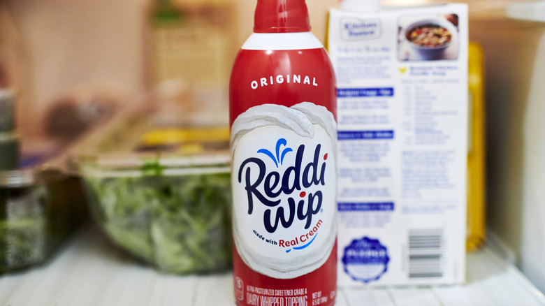 Red and white can of whipped cream inside refrigerator.