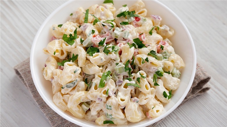 White dish of pasta salad with green herbs