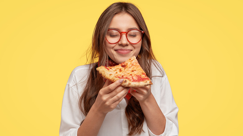 smiling woman with glasses holding pizza