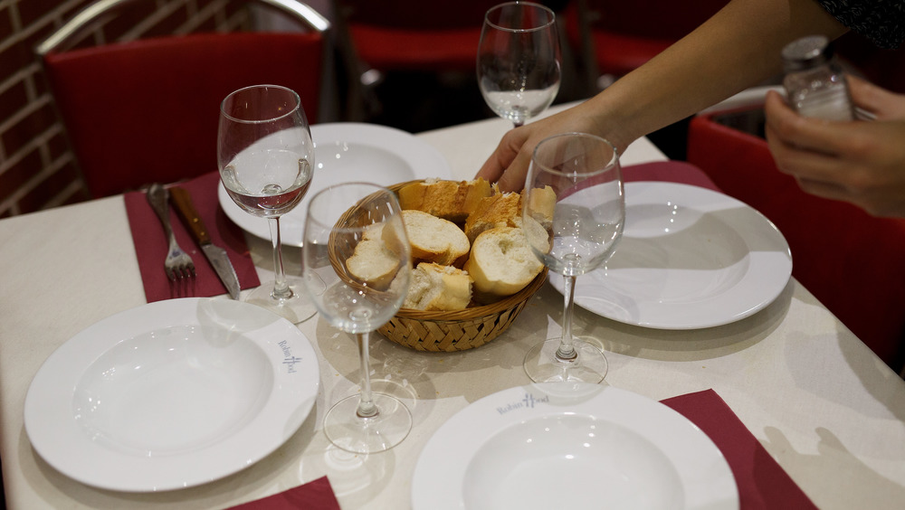 Waitress placing bread in the middle of a table