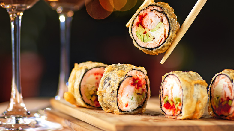 Chopsticks picking up a tempura sushi roll