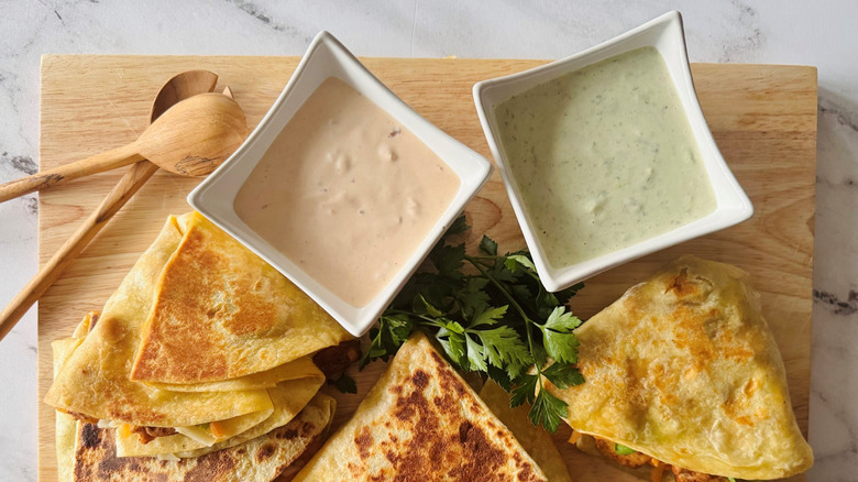 Taco Bell chicken stackers on wooden board next to bowls of sauces