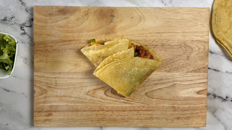 Double-folded stuffed tortilla on wooden board