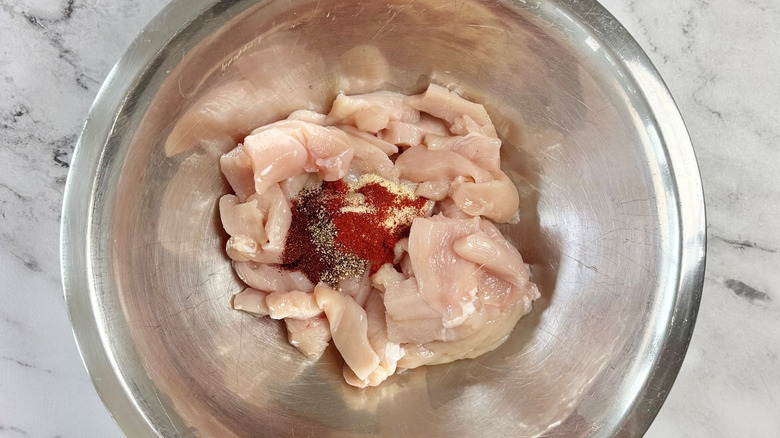 Raw chicken and spices in bowl