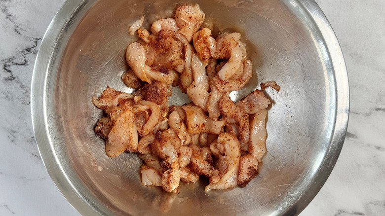 Raw chicken coated in spices in bowl