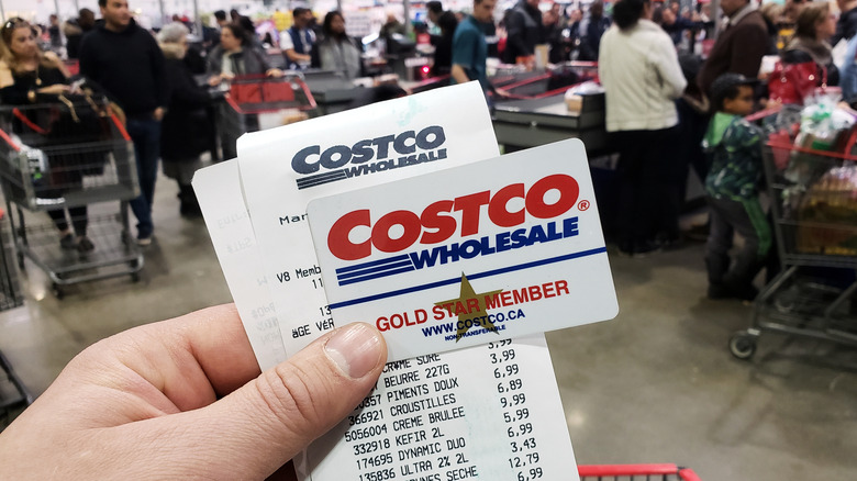 Hand holding up Costco card and receipt in Canada