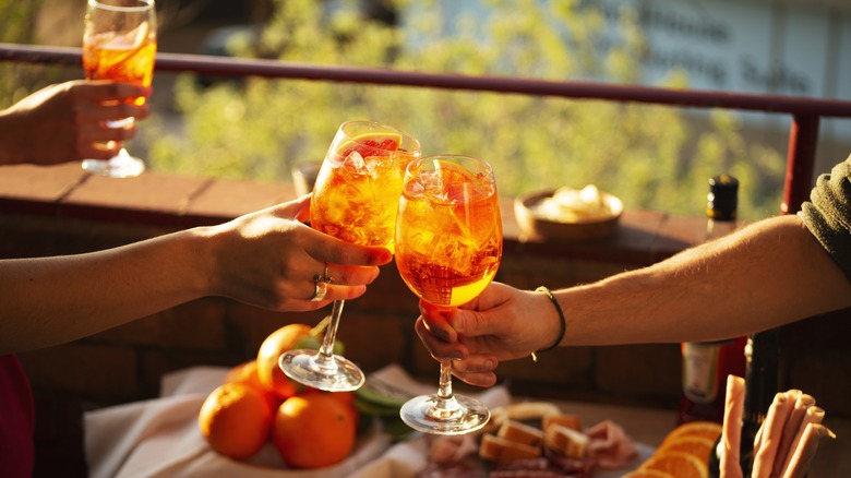 Two people making a toast with Aperol spritz
