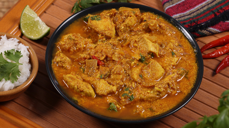 orange curry in a bowl with side of rice