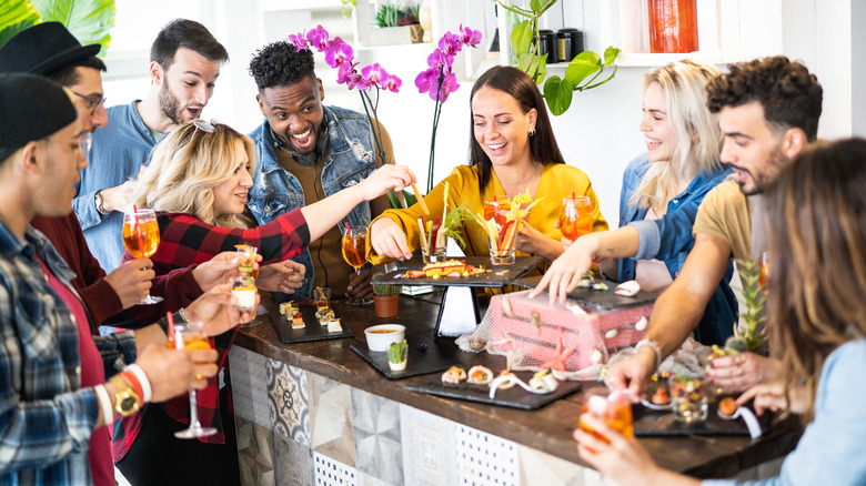 Group of people laughing and enjoying small plates of food