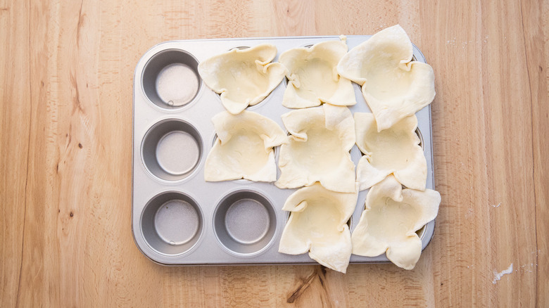 pastry-lined muffin tin on table