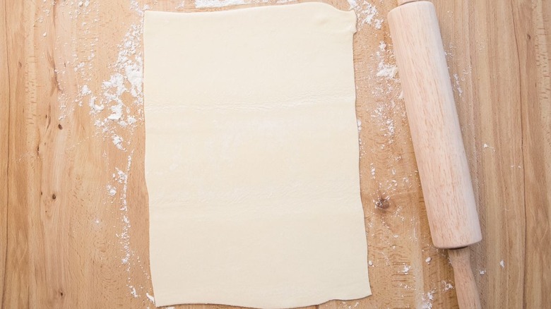 Puff pastry sheet rolled out next to rolling pin