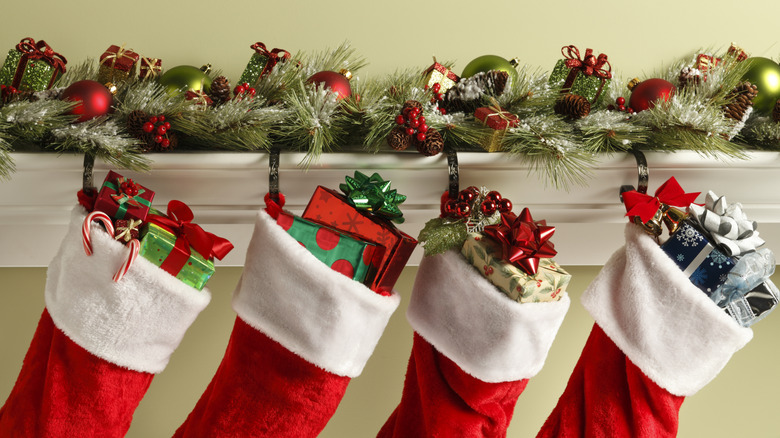 Row of four holiday stockings hung from the mantle and stuffed with presents