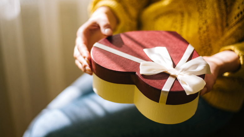Woman holding a box of chocolate with a bow on top