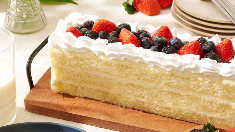 A closeup of a Member's Mark fruit-topped Chantilly cream cake on a cutting board.