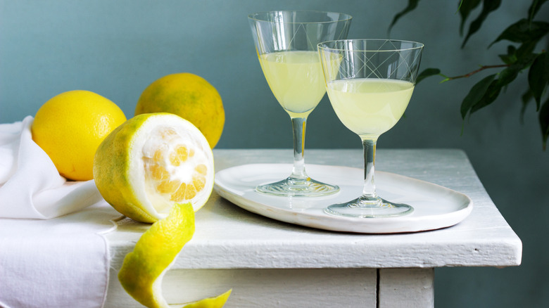 Limoncello in cocktail glasses next to half peeled lemon