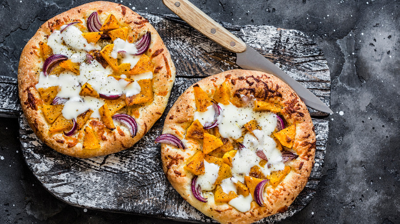 Two pumpkin pizzas with knife