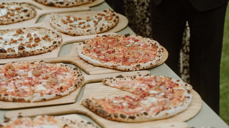 a table covered with pizzas on wooden trays