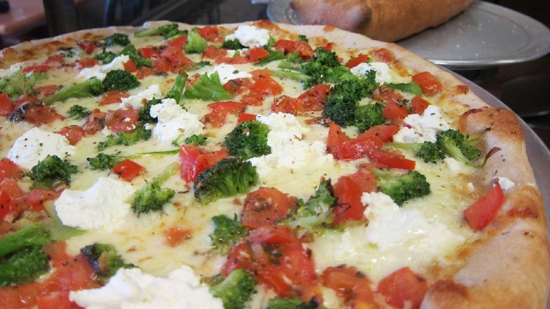 a large pizza with broccoli and tomato