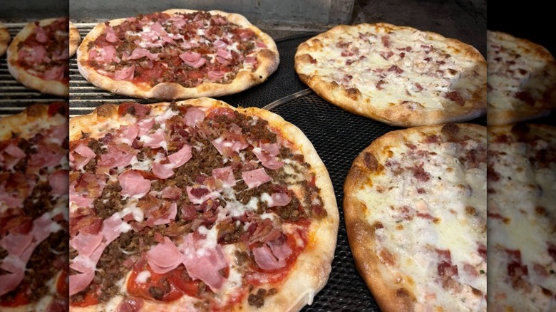 four pizzas with meat, cheese, and tomato toppings