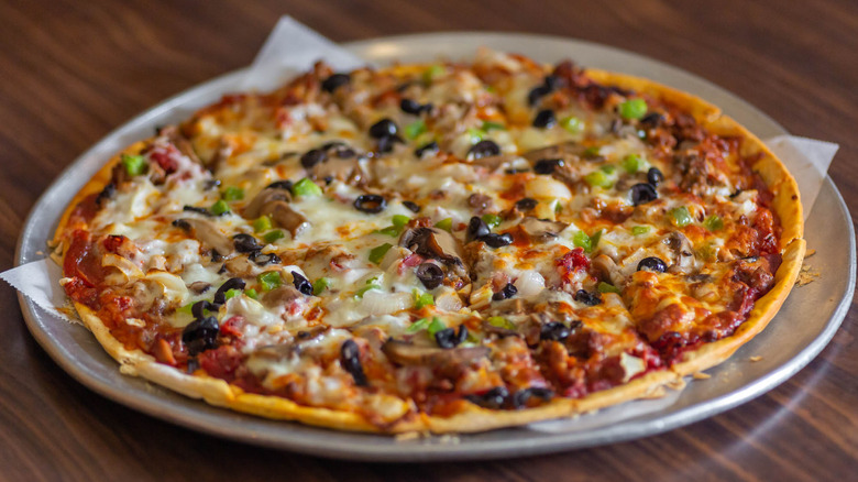 a thin-crust pizza with olives and vegetable toppings