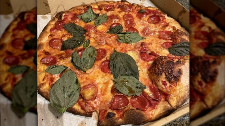 a large pizza in takeout box with pepperoni and fresh basil leaves from Fredi the Pizza Man
