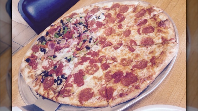 half pepperoni, half everything pizza served on metal pizza tray at Milano's NY Pizza restaurant