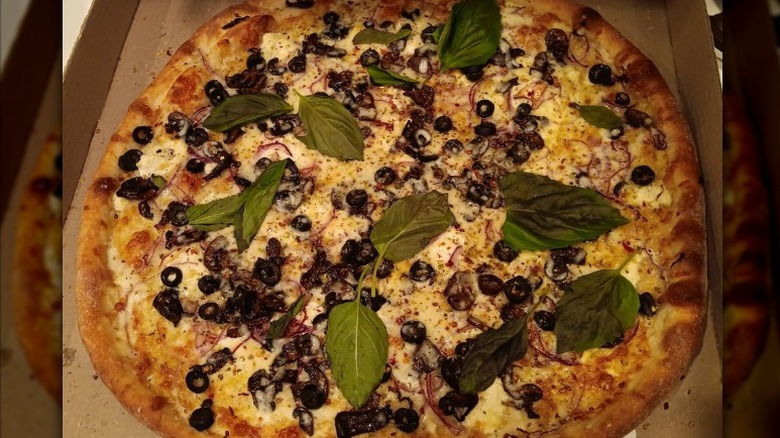Bianca pizza with Mushrooms, Olives, Onions, and fresh basil leaves in takeout box at Dado's Pizza restaurant in Oklahoma