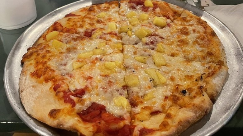 a large pineapple pizza cut in triangles on metal pizza serving tray at Main Street Pizza and Pasta restaurant in Texas