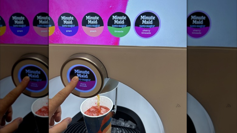 Someone making Minute Maid Freestyle selections on a machine with a cup in the tray