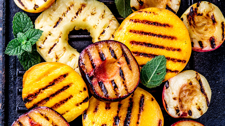 Grilled peaches, pineapple, and plums on a grill