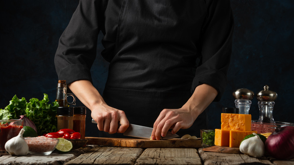 Person cutting food surrounded by ingredients