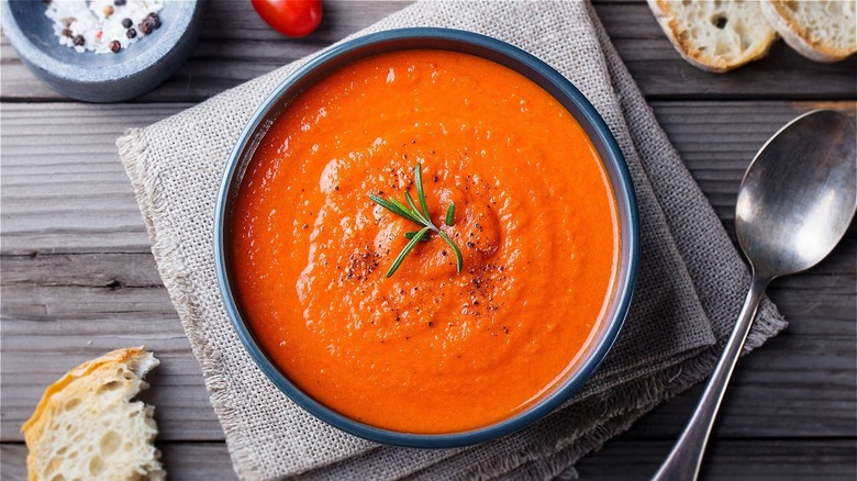 bowl of tomato soup on a table with bread