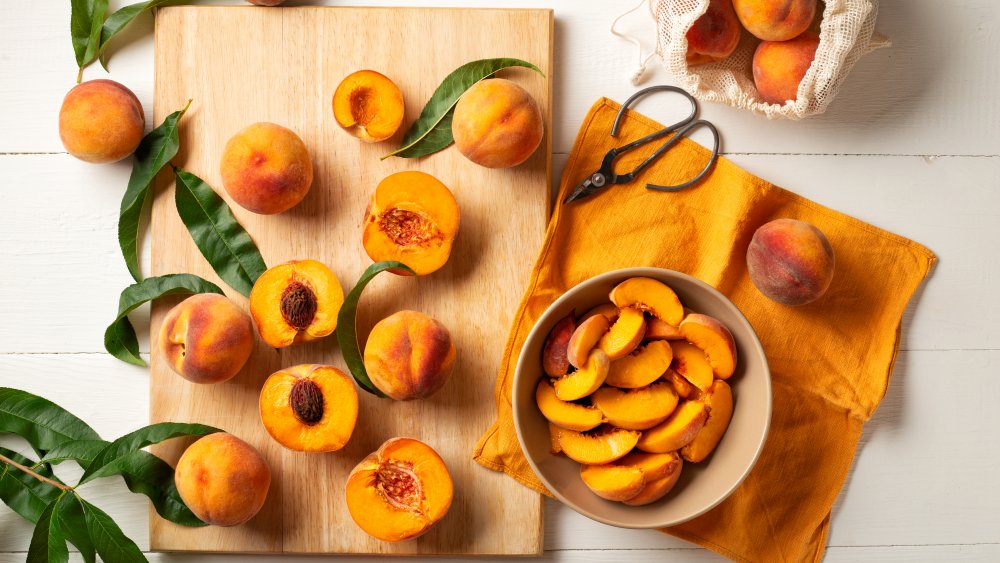 whole peaches and cutting board with halved peaches