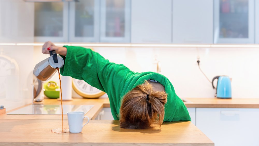 woman asleep at counter trying to pour a cup of coffee