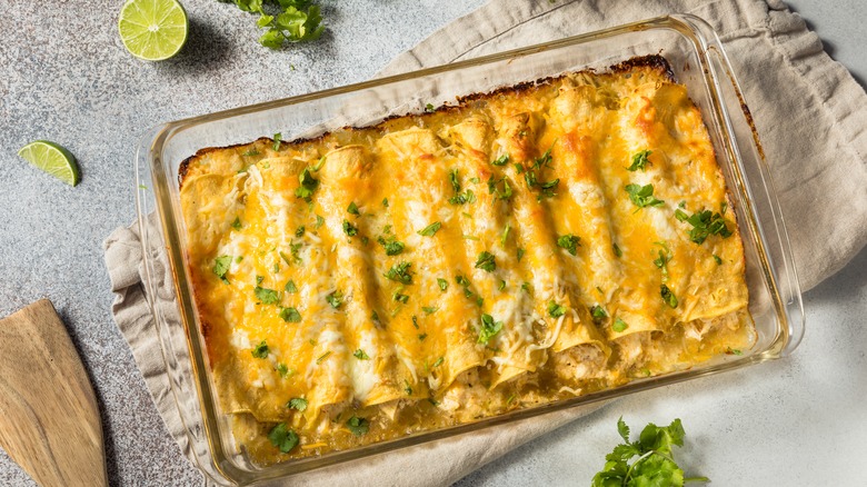 Enchiladas covered with cheese in a glass baking dish