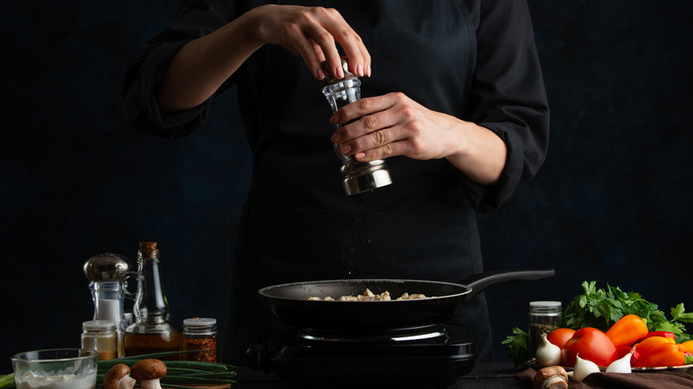 chef salts sautéing mushrooms