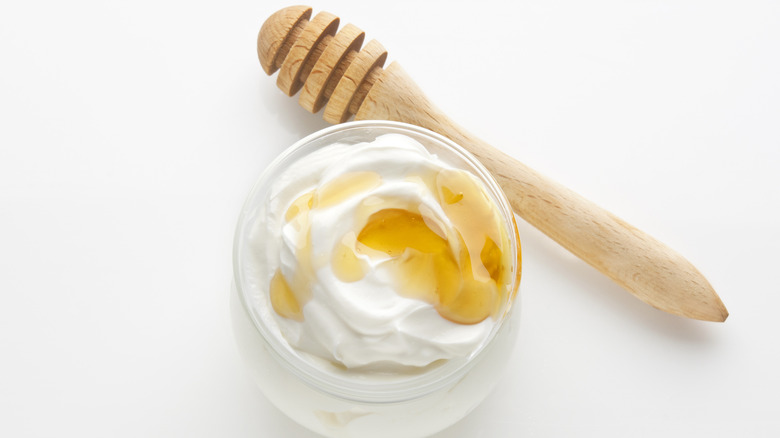 Greek yogurt with honey next to a wooden honey dipper