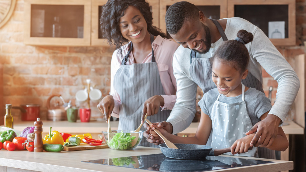 parents and daughter cooking with stove